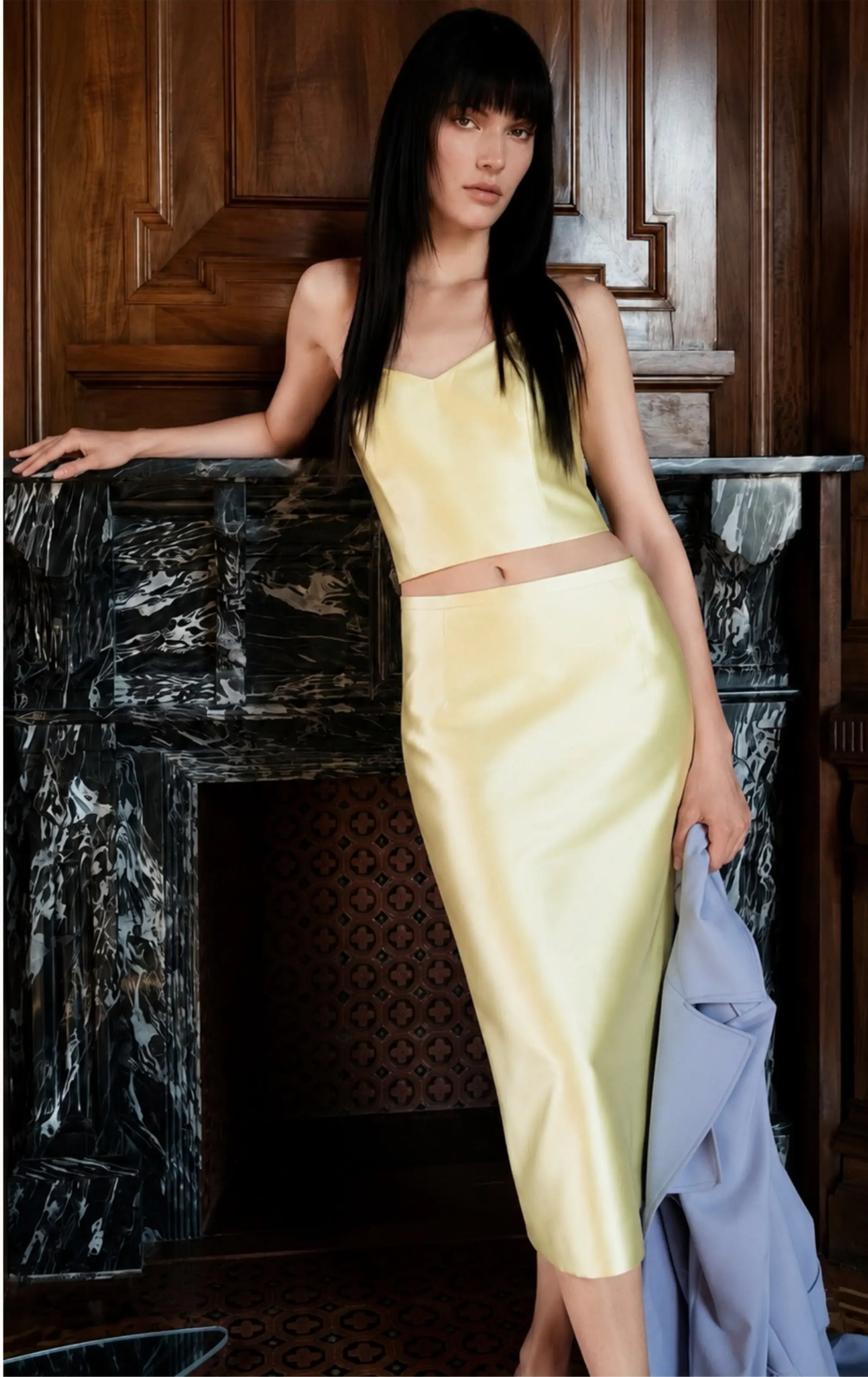 Model in pale yellow outfit in elegant interior